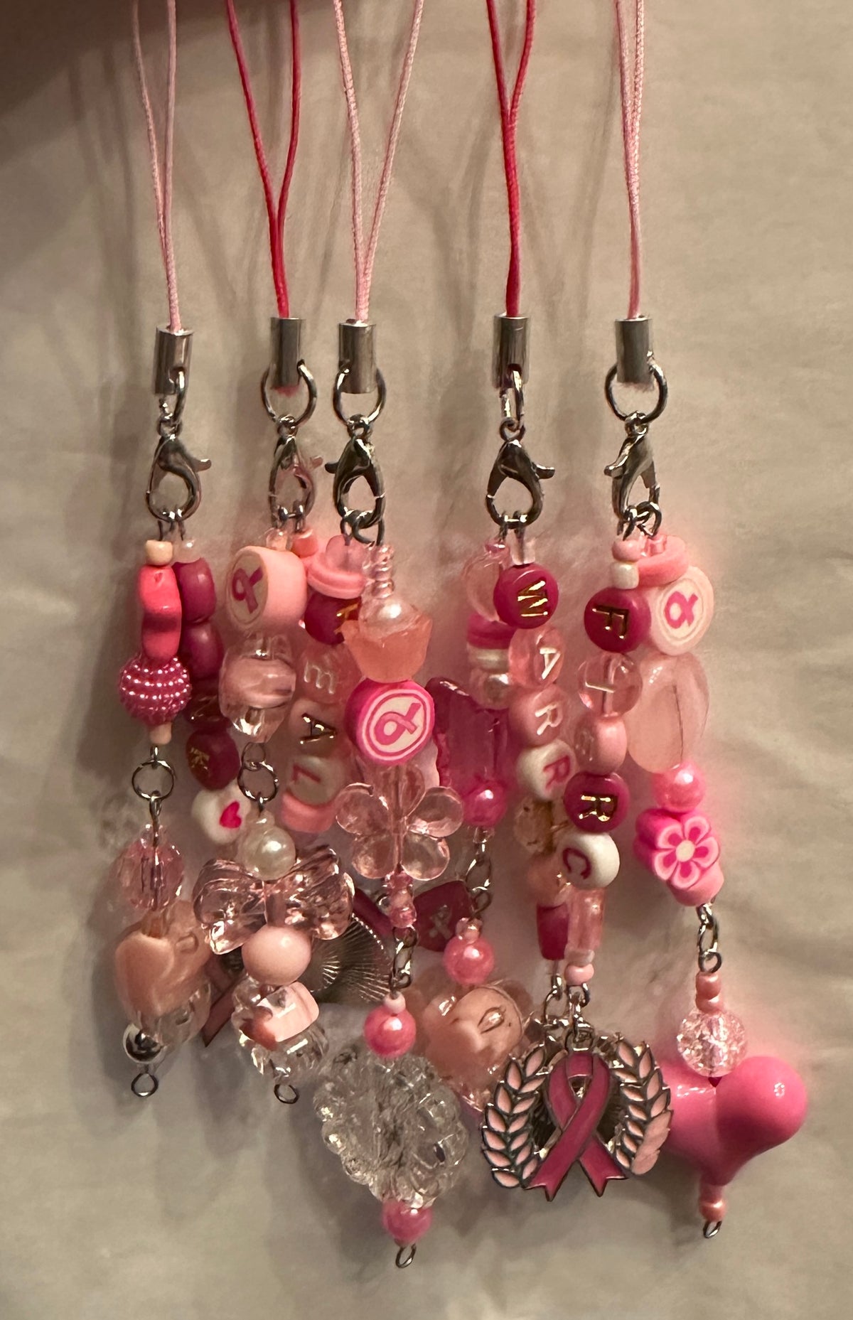 Pink beaded phone strap charms with silver lobster clamps, pink or magenta lanyards.