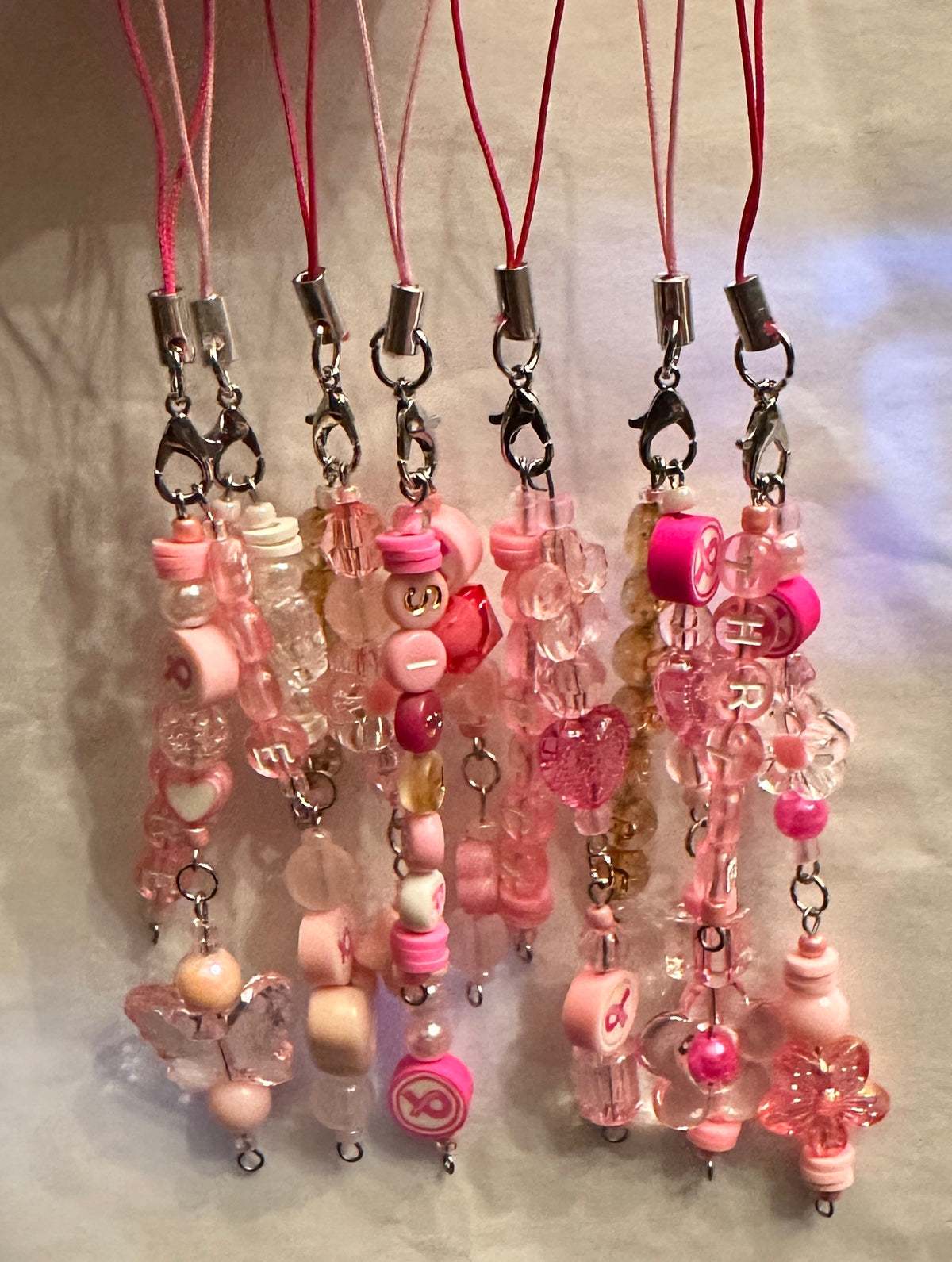 Pink beaded phone strap charms with silver lobster clamps, pink or magenta lanyards.